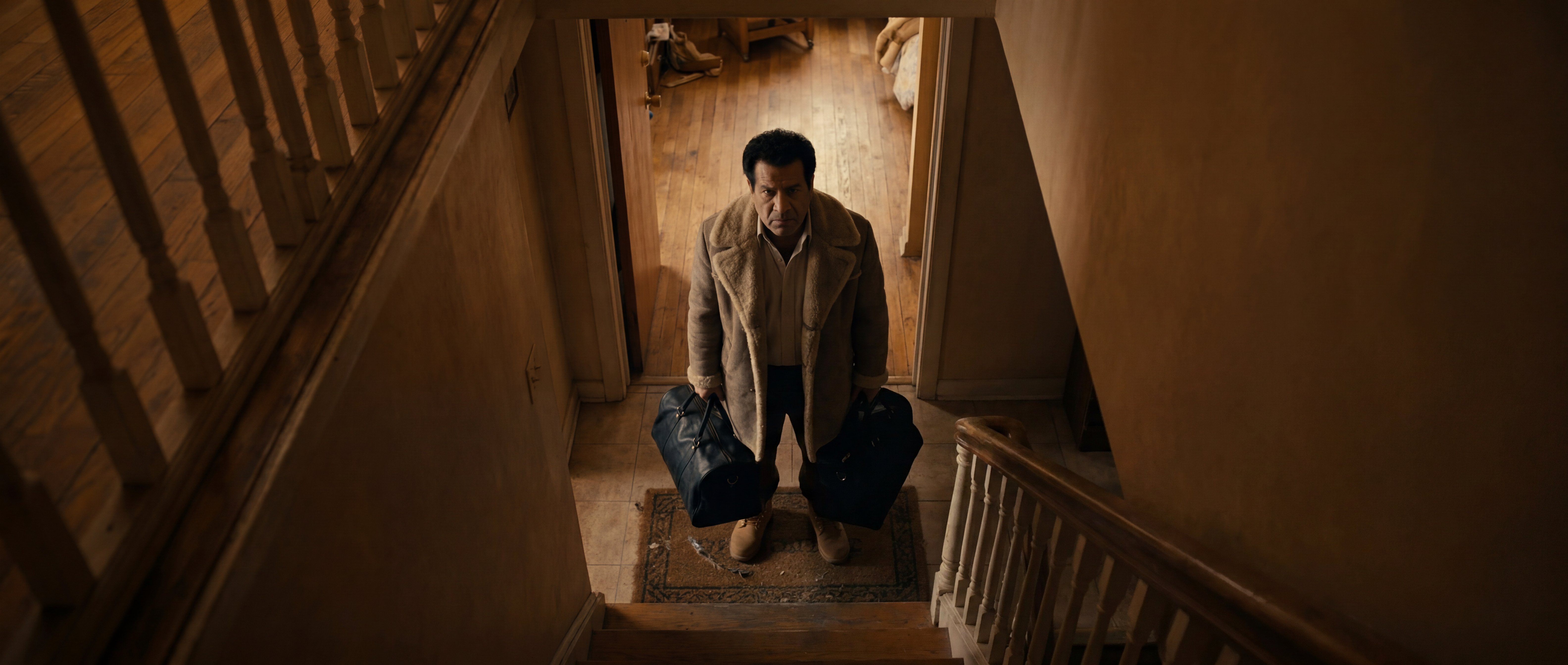 Man with bags at the foot of a staircase